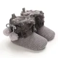 Close-up of adorable grey knitted baby booties with faux fur trim and cute pom-poms - Gray