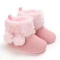 Detailed close-up of pink knitted baby boots with plush faux fur trim and cute pom-poms - Pink