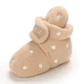 Close-up detail of soft beige plush baby booties featuring an adorable white heart pattern - Apricot