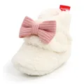 Nahaufnahme eines weißen, flauschigen Baby-Winterstiefels mit rosa Strickschleife - Weiß