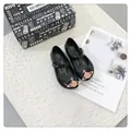 Vista detallada de zapatos de gelatina negros para niñas con logo de planeta oro rosa y caja. - Negro