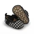 Detailed view of baby princess shoes featuring a classic houndstooth pattern and bow. - Black