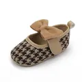 Nahaufnahme brauner Baby-Prinzessinnenschuhe mit Hahnentrittmuster und Schleife - Kaffeebraun
