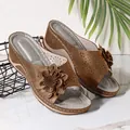 Gros plan de sandales compensées marron avec fleurs décoratives et motifs découpés laser. - Marron