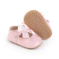 Detailansicht der glänzenden rosa Baby-Prinzessinnen-Schuhe mit großer Schleifendekoration - Rosa