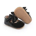 Detail von schwarzen Baby-Lackschuhen mit großer Satinschleife und rutschfester Sohle - Schwarz