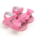 Dettaglio di sandali rosa per neonata con fiocco decorativo e ricamo floreale - Rosso rosa