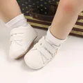 Nahaufnahme von weißen Baby-Lauflernschuhen mit Klettverschluss an den Füßen - Weiß