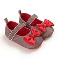 Detailed macro view of infant Mary Jane walking shoes with large red satin bow ornament - Red