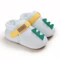 Gros plan de chaussures bébé bleu clair avec pointes de dinosaure et bride jaune. - Bleu clair