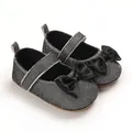 Detailed view of silver glitter baby Mary Jane shoes featuring elegant black satin bows - Black