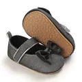 Detailansicht silberner Glitzer Baby Schuhe mit schwarzer Schleife und rutschfester Sohle. - Schwarz