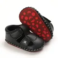 Detail view of the soft black leather material and red non-slip soles of infant sandals - Black