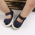 Close-up van donkerblauwe babysandalen met stippen en schattige decoratieve strikjes. - Donkerblauw