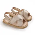 Primer plano de sandalias para bebé color oro champán con suelas blandas y correas. - Dorado
