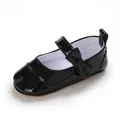 Close-up detail of black patent leather baby girl Mary Jane shoes with decorative bow - Black