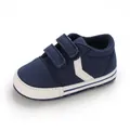 Vista detallada de zapatos de bebé azul marino con suela blanca blanda y cierre velcro. - Azul