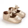 Nahaufnahme goldener Baby-Prinzessinenschuhe mit Metallic-Finish und Schleife - Gold