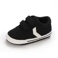 Primer plano de zapatillas de lona negra para bebé con suelas blancas suaves y velcro. - Negro