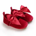 Vista detallada de zapatos de bebé en terciopelo rojo con suela blanda y lazos. - Rojo
