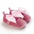 Detalle de zapatos de princesa de terciopelo rosa para bebé con gran lazo de satén rosa. - Rosa