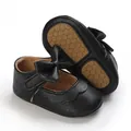 Close-up detail of black baby girl walking shoes featuring soft rubber sole and bow - 11cm / Black