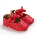 Nahaufnahme der roten Baby-Prinzessin-Lauflernschuhe mit Schleife und Wellenrand - Rot