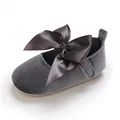 Détail de chaussure de princesse en velours gris pour bébé avec un grand nœud. - Gris