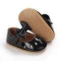 Detail of black patent baby girl princess walking shoes featuring a bow and soft rubber sole - Black