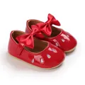 Gros plan de chaussures de marche rouges pour bébé avec nœud en satin et paillettes - Rouge