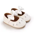 Détail des chaussures de princesse pour bébé fille avec nœud en satin et paillettes. - Blanc