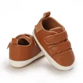 Detail view of brown faux leather baby shoes with white soles and velcro straps - Brown