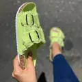 Detailed view of lime green canvas slide sandals with fringe edges and metal buckles. - Light Green