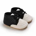 Close-up detail of black and white infant walking shoes with soft anti-slip rubber soles - Black and White