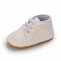 Primo piano di scarpe per neonati bianco crema con dettagli brogue e suola morbida antiscivolo - Bianco