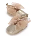 Detaillierte Nahaufnahme goldener Baby-Prinzessin-Schuhe mit einer großen Netzschleife - Gold