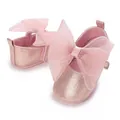 Detailaufnahme der rosa glitzernden Baby-Prinzessin-Schuhe mit großer Organzaschleife - Rosa