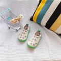 Close-up detail of baby walker shoes with green avocado print and soft rubber soles. - Avocado
