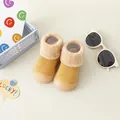 Nahaufnahme von warmen gelben Strick-Babysöckchen mit Plüschkragen und weicher Gummisohle. - Gelb