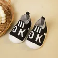 Atmungsaktive schwarz gestrickte Babylauflernschuhe mit weichen weißen Sohlen und OK-Muster - Schwarzer Buchstabe OK