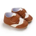 Detailed view of brown and white baby walking shoes with elegant brogue perforation details - Brown