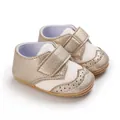 Detailed shot of champagne gold baby walking shoes featuring brogue patterns and Velcro - Gold