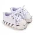 Nahaufnahme von weißen Canvas-Babyschuhen mit weicher und rutschfester Gummisohle - Weiß