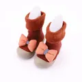 Dettaglio scarpe calzino neonato in maglia con risvolto in peluche e fiocco arancione. - arancio-rosso