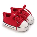 Detaillierte Nahaufnahme roter Segeltuch-Babyschuhe mit Textur und weißer Gummisohle - Rot
