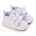 Vista detallada de zapatos blancos para bebé con grandes lazos decorativos con volantes. - Blanco