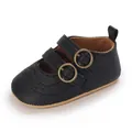 Detailed view of black baby Mary Jane shoes with double buckle straps and broguing. - Black