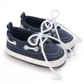 Vista detallada de zapatos de bebé azul marino con suelas blancas flexibles y cordones blancos. - Azul marino