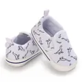 Detailweergave van witte baby canvas schoenen met blauwe dinosauriër patroon print. - Wit