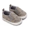 Close-up of baby canvas walking shoes with dinosaur print and white soft rubber soles - Gray